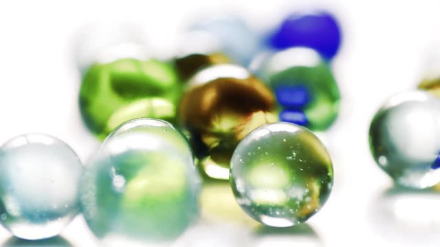 Colorful rolling glass marbles on white background.