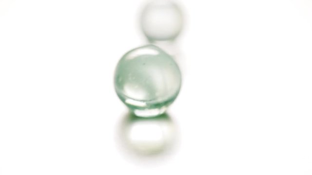 Colorful rolling glass marbles on white background.
