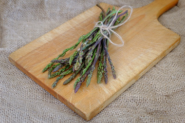 Bunch of raw wild asparagus on a wooden chopping board