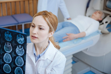 Serious female oncologist examining results of the CT scan