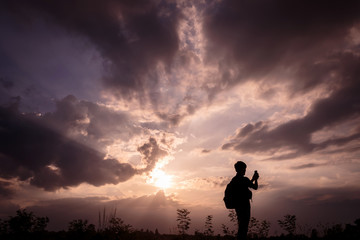 Silhouette man with backpack use smartphone in hands at sunset background, Travel concept.