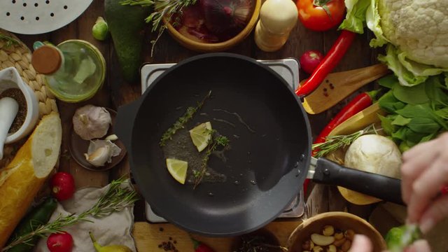 Time lapse footage. Top view of male hand frying piece of lemon and herbs on pan and then adding salmon steak