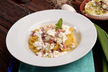 Dish of pasta noodles with cottage cheese bacon and onion shallot
