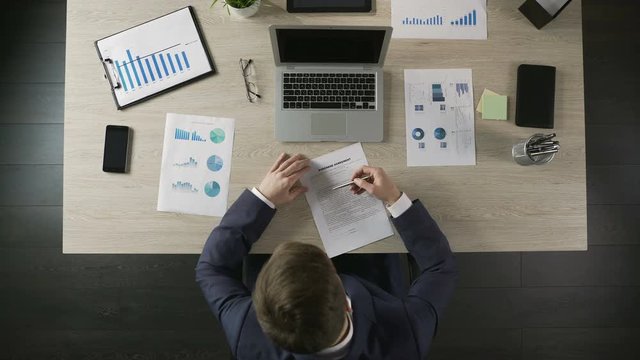 Serious businessman reading and signing purchase agreement, public procurement