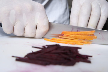 The cook cuts the carrot on the board