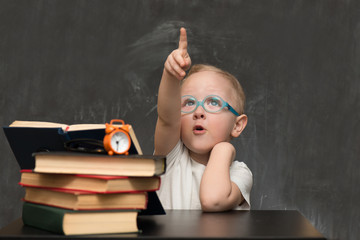 child dressed in Glasses sitting at table with books