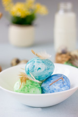Green, yellow and blue easter eggs on ceramic bowl, bright and airy shot.