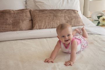 Portrait of baby girl smile on bed indoors with copy space.