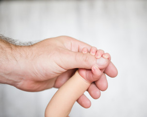 Newborn baby holding father's hand