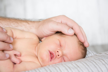 Father's hand stroking a newborn baby