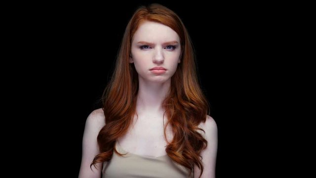 Frustrated frowning young red haired woman saying no isolated over black 