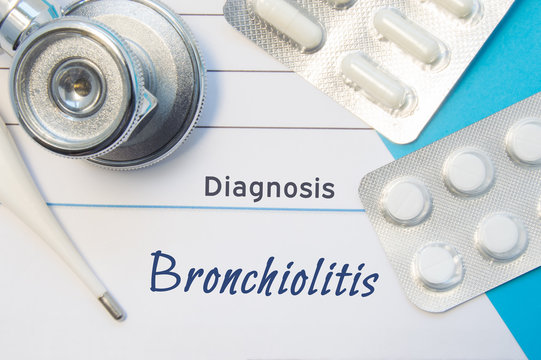 Diagnosis Bronchiolitis. Doctor's stethoscope, electronic thermometer and two blisters of pills lying near pad with inscription of diagnosis Bronchiolitis. Concept of report in internal medicine