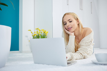 Young woman using laptop on bedroom