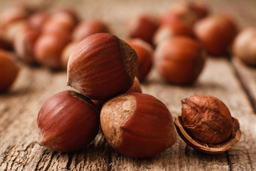 Full and peeled hazelnuts close-up. Macro photo of pile of filbert kernels, lot of nuts on blurred background. Bright autumn backdrop. Harvest, fall, food ingredient concept