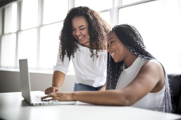 Two teen at desk in her office with laptop