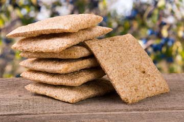 stack of crisp bread on a wooden table with blurred garden background