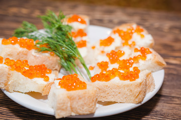 Red caviar. Caviar on a piece of bread and butter. A delicacy caviar with oil on a table.