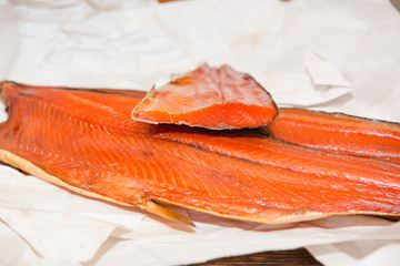 Red fish on a table. The fish packed into paper on a table. Salmon smoked.