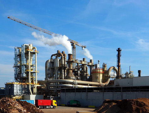 Industrial plant with smoke stacks, pipes and a crane