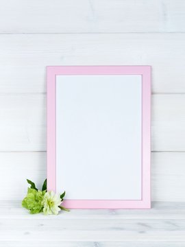 Flowers and a photo frame on a wooden background.