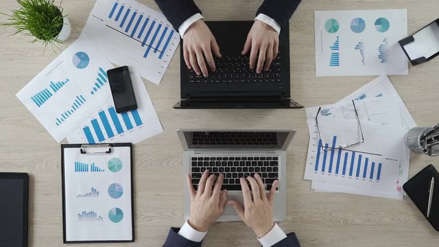 Hands of business partners typing on laptops opposite each other, negotiations