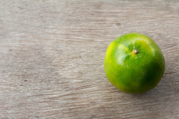 One green color lime on wooden table background