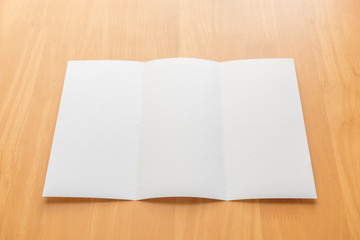 Trifold white template paper on wood background