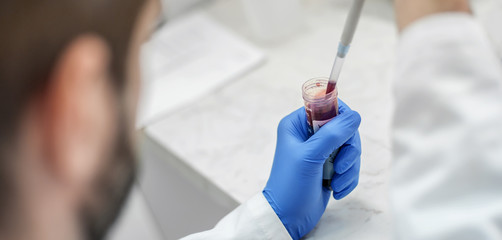 Scientist filling test tubes with pipette in laboratory
