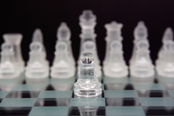 glass chess on a black background. One pawn against the opponent's pieces.