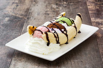 Banana split ice cream dessert with chocolate syrup on wooden background

