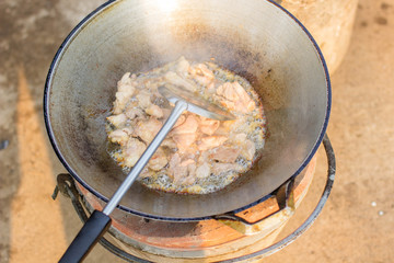 Frying pork on pot with boiling oil.delicious food, pork graves on the pot,cooking the food with pork,old pot on the stove with boiling oil.