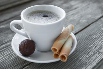 Cup of coffee with cookies on wooden table.