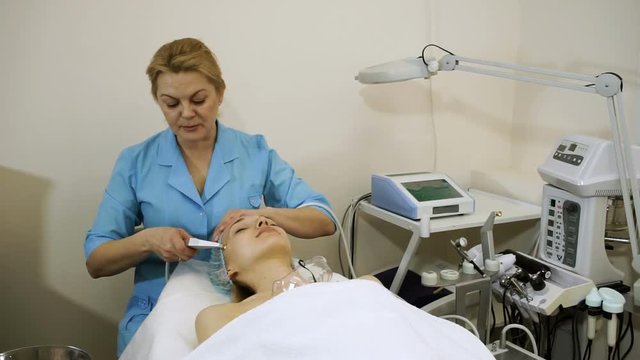A young woman at the beautician. Female doctor giving beauty treatments to face skin. HD