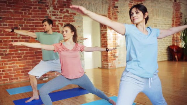 group of people making yoga exercises in gym