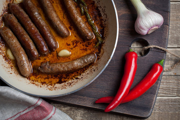 Grilled lamb sausage with rosemary and garlic in a frying pan in olive oil.