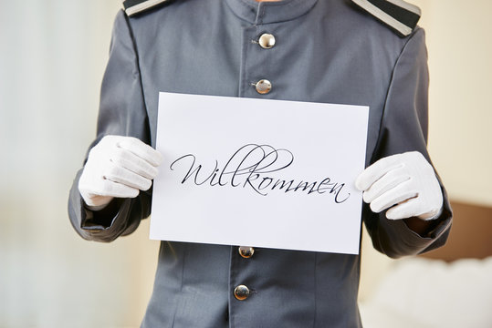 Hotel clerk holding German Willkommen sign