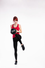 Fototapeta premium Fitness woman in red tank top holding medicine ball. Studio shot