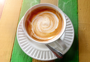 Hot cappuccino coffee on the wooden table.