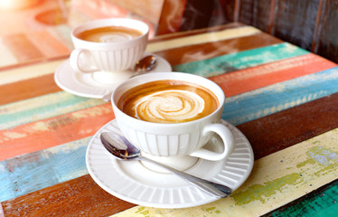 Hot cappuccino coffee on the wooden table.