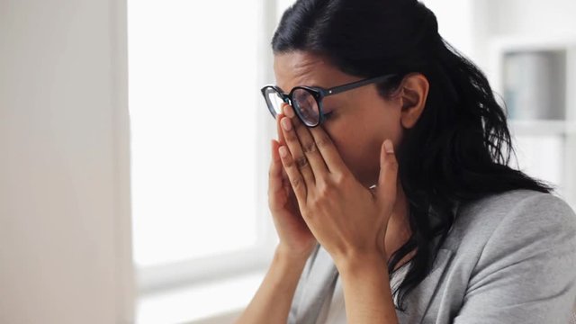 businesswoman rubbing tired eyes at office