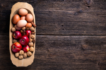 Wooden bowl with apple, eggs and walnut