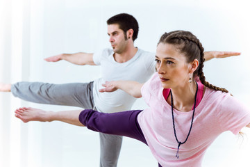 Beautiful young couple practicing yoga at home.