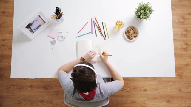 woman drawing picture in notebook at home desk