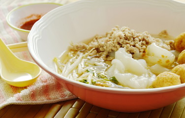 large noodles topping boiled minced pork and shrimp ball in soup with chili sauce