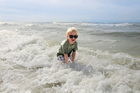 Happy Child Playing Outside in the Ocean Waves