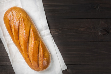 Fresh bread on cloth against dark wooden background. Top view
