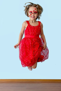 Little girl with ladybug face paint jumping