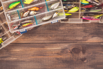 Fishing tackle boxes on wooden background with free space. Top view