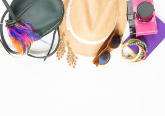 Holiday/travel background. Hipster stuff. Green cross bag, straw hat, retro brown sunglasses, colorful headband, pink retro camera, boho bracelet and earrings. Flat lay, top view.