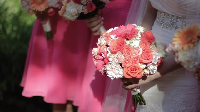 Bride holding a bouquet of white and orange flowers, rack focus